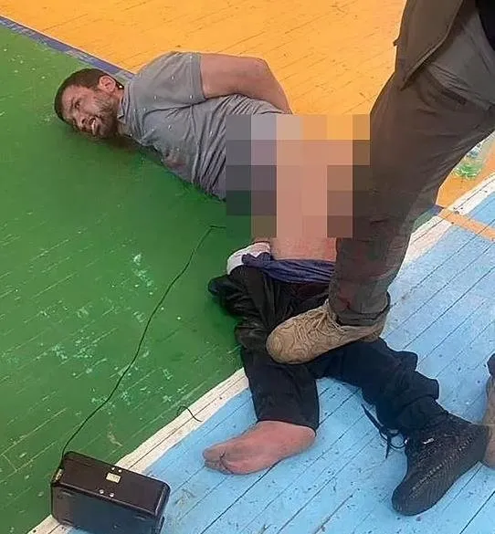 Şüpheli teröristlerden biri olan Fariduni Şamsidin, spor salonunun zemininde pantolonu indirilmiş ve kasık bölgesine teller bağlanmış halde yatarken.