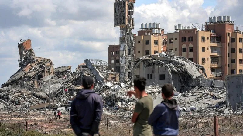Gençler, Gazze Şeridi'ndeki Nuseyrat'ın kuzeybatısındaki Asra yerleşim yerinde yıkılan binaların enkazını arayan insanları uzaktan izliyor, 25 Mart 2024
