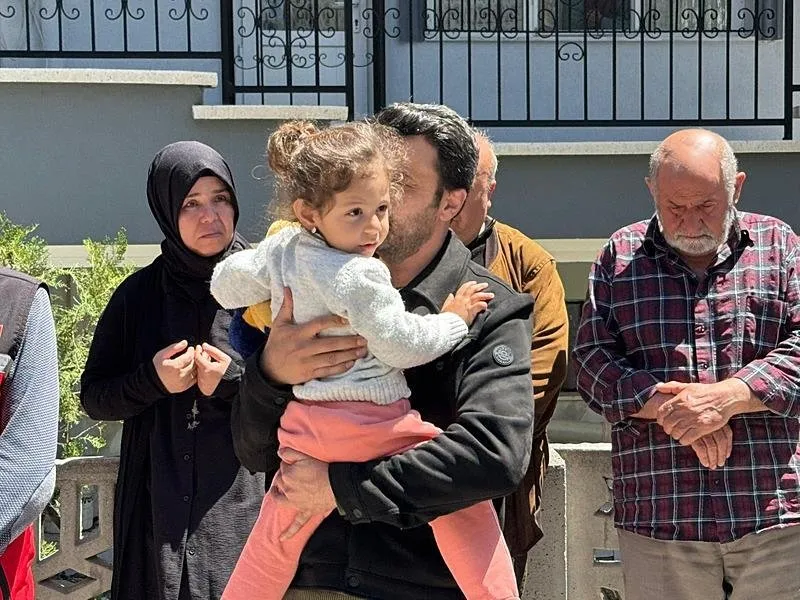 Şehidin kızı Alya (4), Aile ve Sosyal Hizmetler İl Müdürlüğü personelinin kucağında babasının naaşına yaklaşarak elindeki oyuncağı gösterdi. (AA)