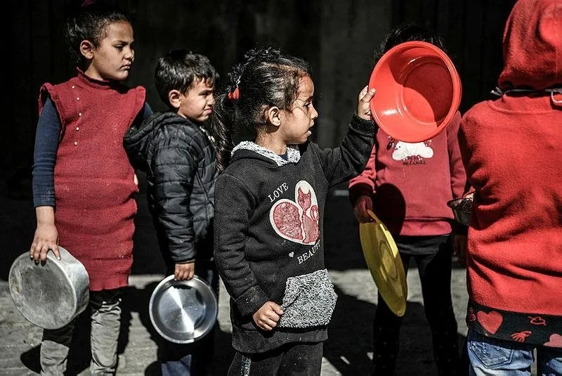 Saldırılar nedeniyle aileleriyle birlikte Refah kentine sığınan çocuklar, hayır kurumlarının dağıttığı yemeklerden alabilmek için bekliyor