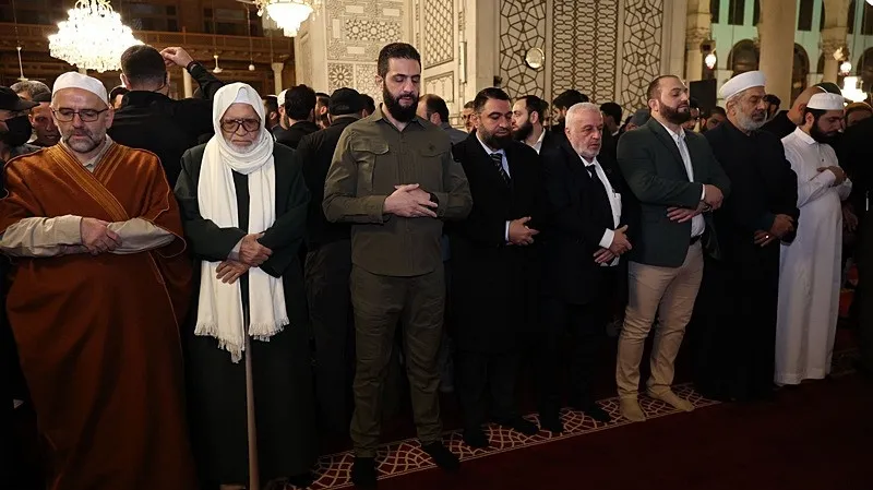 . Geçen yıl Şam'a girdiği askeri kıyafetle camiye gelen Şara'ya, Dışişleri Esad Hasan Şeybani'nin de bulunduğu bazı bakanlar da eşlik etti. (AA)